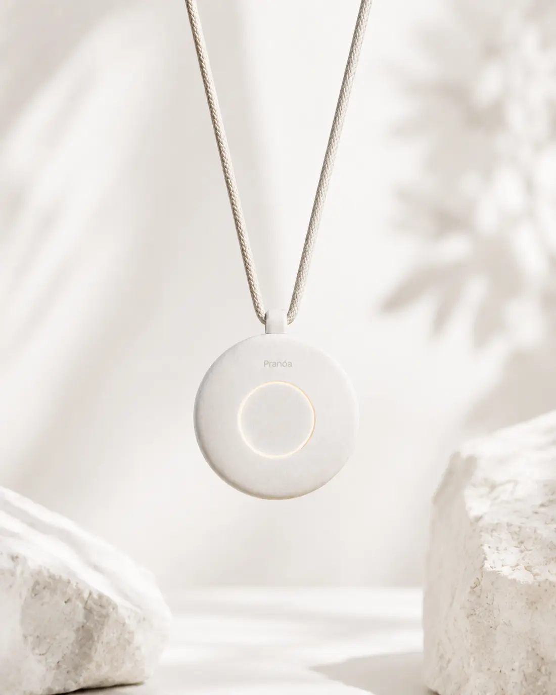 The Pranōa pendant in white, hanging from its woven cord
